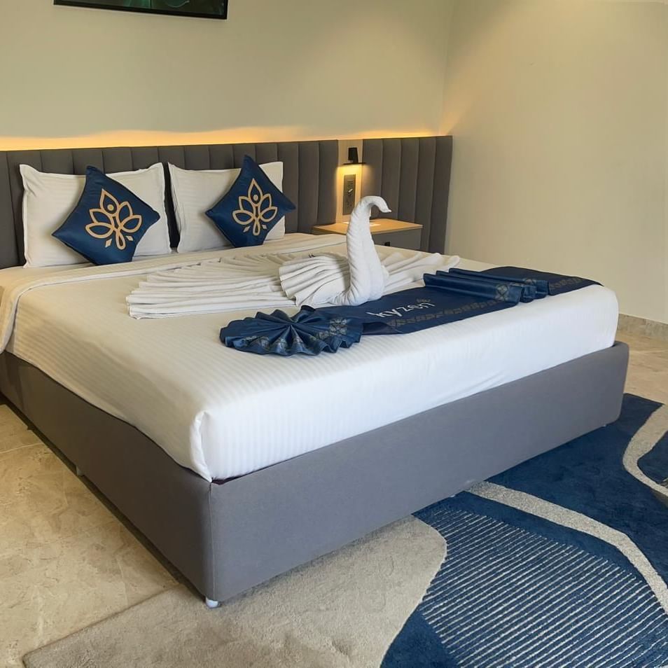 Bedroom at Hotel Kyzen HiTech City with a king bed on a blue decorative carpet.